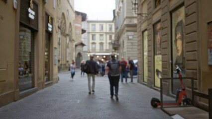Narrow european street defocused bokeh with blurred storefronts, cobblestone pavement and parked scooter; background copyspace overlay calm.