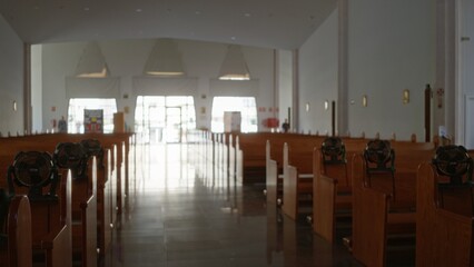 Defocused church interior with shallow focus, wooden pews lining an empty central aisle and bright entrance at rear; background backplate copyspace calm.