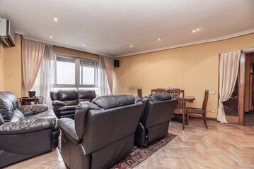 living and dining room with a black leather sofa, a metal coffee table, and a dining table with steel legs.