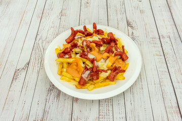 Venezuelan salchipapas with sliced ​​sausages, crispy fries, pink sauce, mustard, and diced avocado