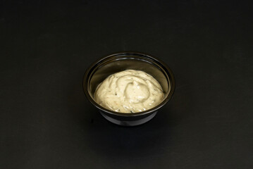 Mini ceramic containers with garlic mayonnaise, decorated with freshly chopped parsley to contrast with the white of the sauce
