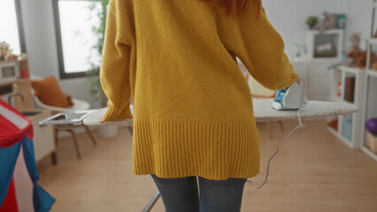 Woman ironing in a cozy laundry room with modern decor, wearing a yellow sweater, surrounded by...