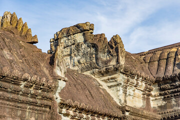 Obraz premium Close-up of ancient roof pediment carvings with naga on angkor wat temple in siem reap, cambodia, showing weathered sandstone detail in warm morning light