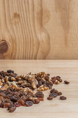 Autumn still life with raw almonds, black raisins, split walnuts, and goji berries on an aged oak board