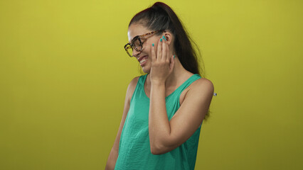 Woman pressing hand to cheek and wincing with visible toothache in lime green studio, wearing glasses; toothache pain.