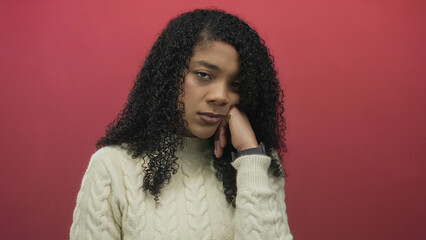 Woman leaning head on hand in studio wearing a white cable knit sweater and curly hair with closed...