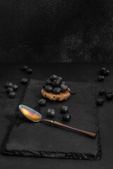 Close-up of wild blueberries on a black velvet background and a sterling silver spoon with decorative engravings