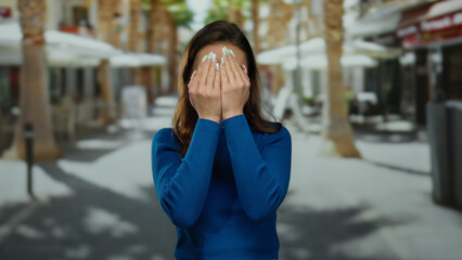 Fototapeta premium Young woman wearing vote badge in a blue shirt making funny faces on a sunny city street in the united states.