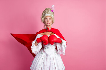 Sophisticated noblewoman in a historical gown with red boxing gloves against a pink background...