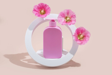 Pink cosmetic bottle with flowers in modern circular frame on pastel background.