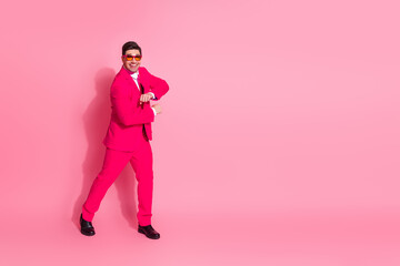 Vibrant man in a bold pink suit with sunglasses dancing against a pink background exuding humor and charm.
