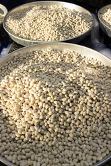 Heap of freshly peeled white beans in a metal tray, glossy texture and tight vertical frame; for food design, retail promotion, recipe blog, education.