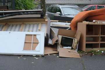 Pile of discarded household items on the street, including a door, couch, microwave, and wooden shelves.