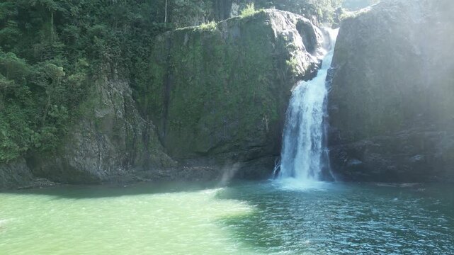 4K drone footage of Jimenoa Waterfall cascading through lush tropical forest in bright sunlight — perfect for travel, adventure, and eco-documentary visuals