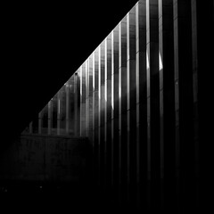 Naklejka premium High-contrast monochrome photo of city architecture with dramatic light and shadow interplay. Clean lines, geometric balance, and sharp perspective create abstract modern feel suitable