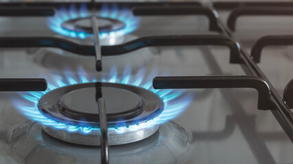 Close-up of a blue fire from a kitchen stove. 4 gas burners with a burning flame. economy concept.