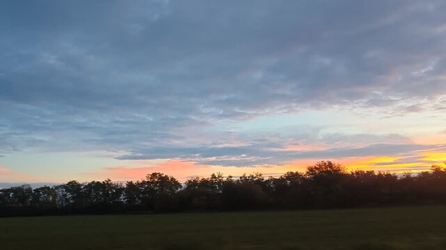 View from Car Window of Passenger Train Moving Through Autumn Landscape at Sunset