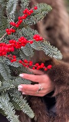 A woman's hand holds a branch of a Christmas tree