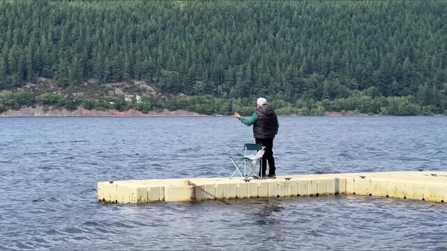 Hombre pescando en muelle flotante, Lago Ness