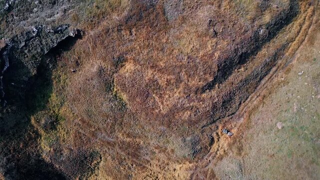 Aerial dry rocky ground with sparse vegetation and scattered stones. Rugged land