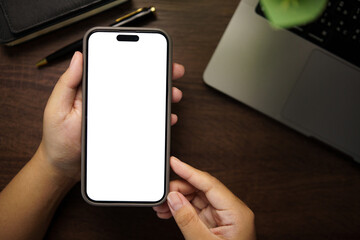 Hands holding smartphone with blank white screen on wooden desk, ready for app mockup or website design.