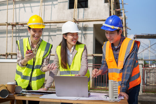 Architectural team analyzing structure model and project drawings at construction area.