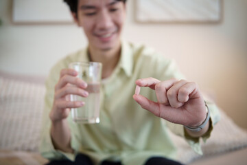 Man preparing to take a vitamin supplement with water. Concept of daily health routine, nutrition, and self care lifestyle.