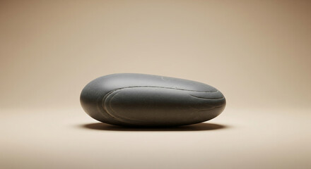A smooth, gray stone resting on a neutral background, showcasing its simple beauty and natural form, ideal for zen or meditation themes
