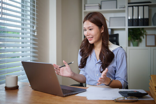 Smiling businesswoman talking during a video call on laptop in modern office.