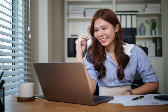 Smiling businesswoman having online meeting or video call on laptop in modern office.