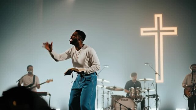 Man leader speaking and singing with band and luminous cross in modern church, christian protestant worship concept video
