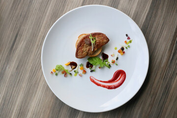 Gourmet dish on a white plate, served on a wooden table 