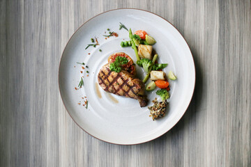A beautifully plated meal, a culinary creation of grilled meat, vegetables and grains, served in a fine dining setting.