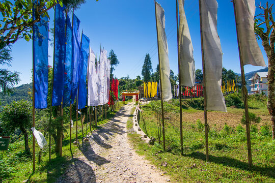 Beautiful colourful gateway to Rinchen Chholing Monastery with colourful Buddist prayer flags, clear blue sky and Himalayan mountains in background. Rinchenpong, Sikkim, India.