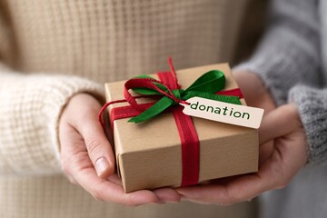 Hands exchanging a wrapped gift with a donation tag for charity
