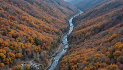 Drone view of mountain range with colorful autumn forest, orange and red trees covering slopes, winding road and river visible below, high-resolution aerial landscape