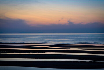 Beautiful sunset over Matama Coast in Oita, Japan, with soft pastel sky reflected on tidal flats and calm sea, creating a serene minimalist seascape filled with tranquility and natural harmony