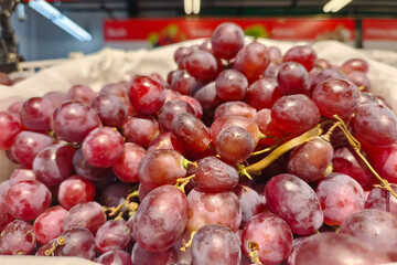 Close-up shot of fresh red grapes arranged in a crate at the supermarket, showing natural texture...