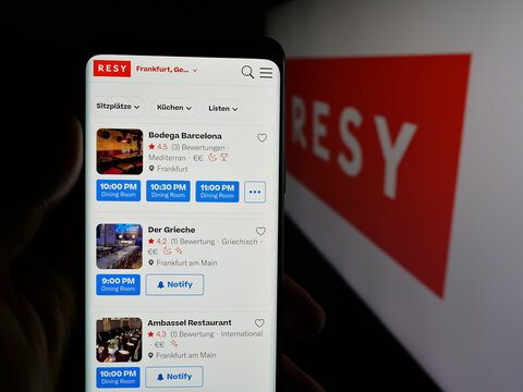 Stuttgart, Germany - 10-18-2025: Person holding cellphone with webpage of US restaurant reservation company Resy on screen in front of logo. Focus on center of phone display.