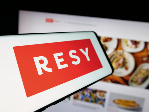 Stuttgart, Germany - 10-18-2025: Smartphone with logo of US restaurant reservation company Resy on screen in front of website. Focus on center-left of phone display.