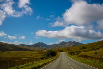 Lonely road leading toward Mount Snowdon under blue sky, Snowdonia, Wales