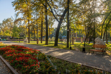 Flowers in park at Bishkek Oak Park with tall autumn trees, and seasonal garden colors.
