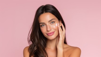 Portrait of a Smiling Woman Applying Skincare Cream on Her Face Against a Soft Pink Background
