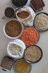 Bowls and bags full of various healthy grains and legumes. Top view.