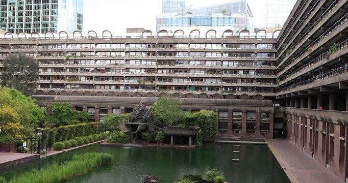 High angle view of Barbican water garden in London: concrete walkways, planted islands and green reeds in emerald water.