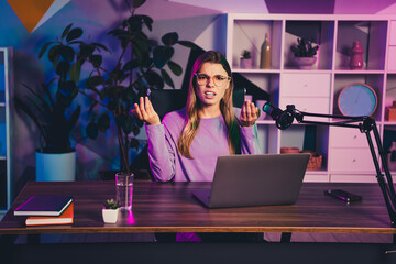 Radio host in a modern home office with vibrant neon lighting expressing emotions during a live...