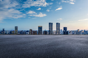 Empty asphalt platform overlooking the modern city skyline and commercial buildings on a clear day.