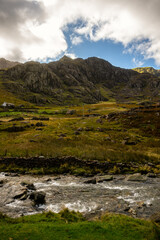 Flowing mountain stream beneath rocky cliffs in Snowdonia, Wales