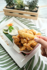 Crispy fried chicken pieces served on a plate, a hand is picking a piece of fried chicken