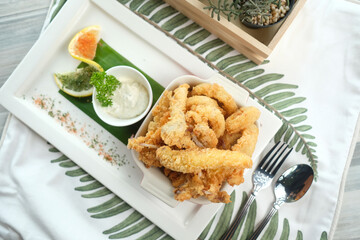 Golden fried calamari served with lemon slices, parsley, and dipping sauce. This image evokes feelings of warmth and satisfaction, perfect for food-related projects.